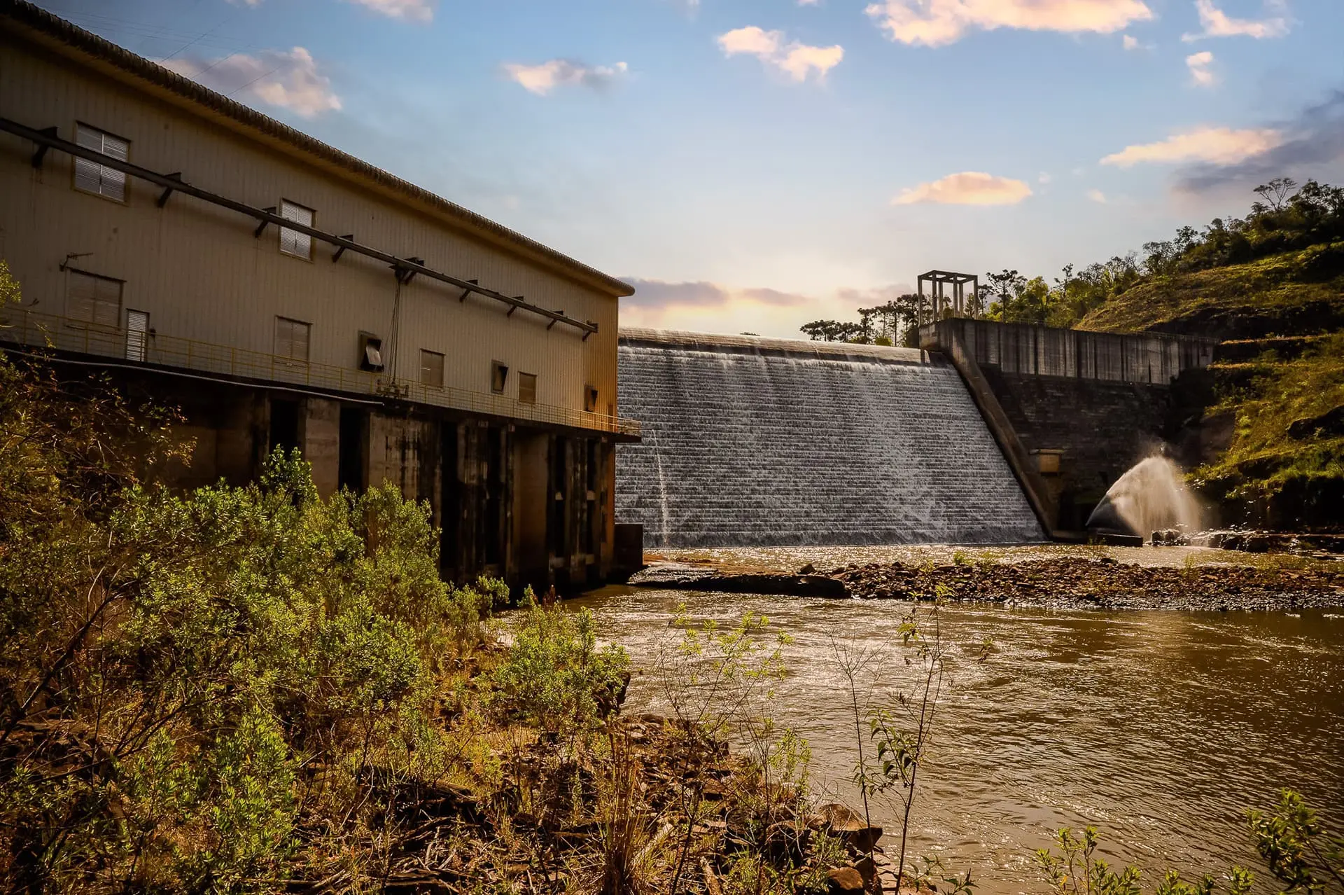 Usina geradora de energia elétrica da Coprel com água ao fundo.